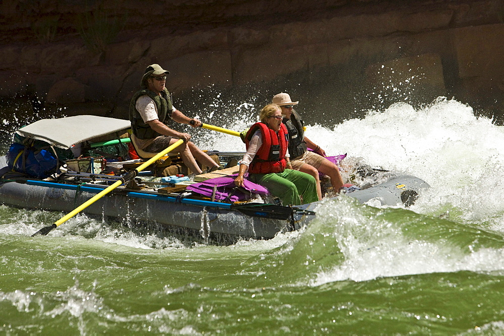 A river guide navigates his boat through rapids.