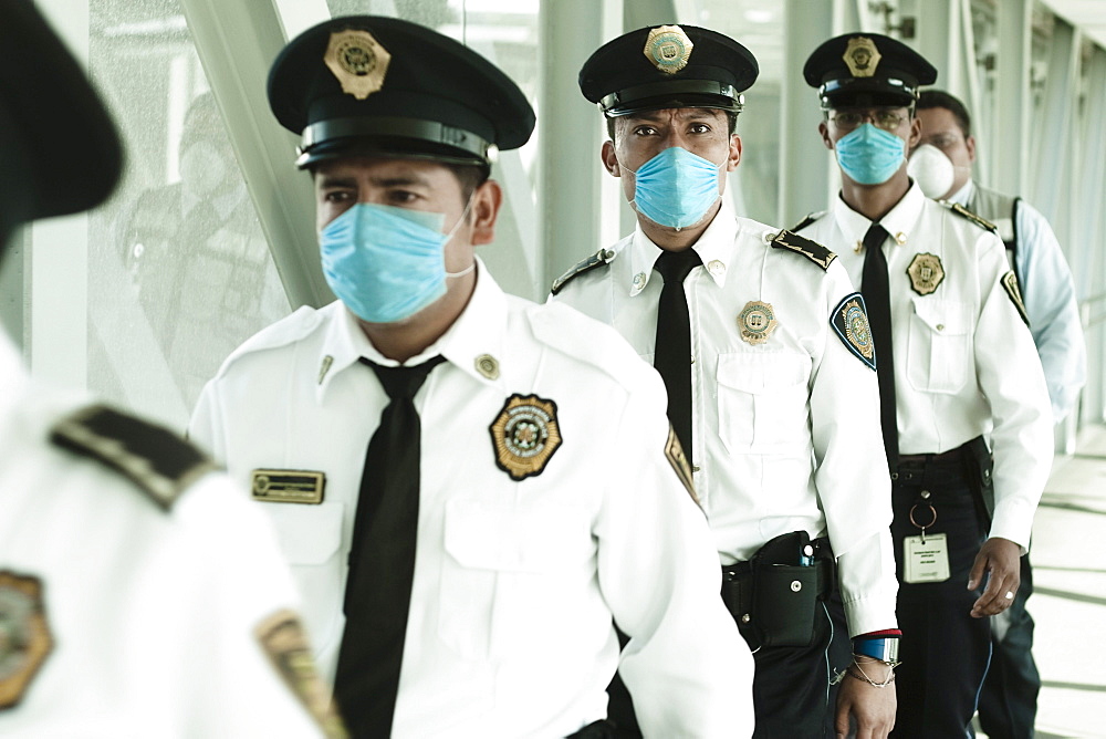 Policemen walking at the airport wearing blue masks. Mexico city, DF, Mexico.