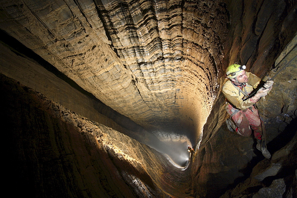 A man ascends the ropes in the largest underground shaft in the world called Miao Keng in China.