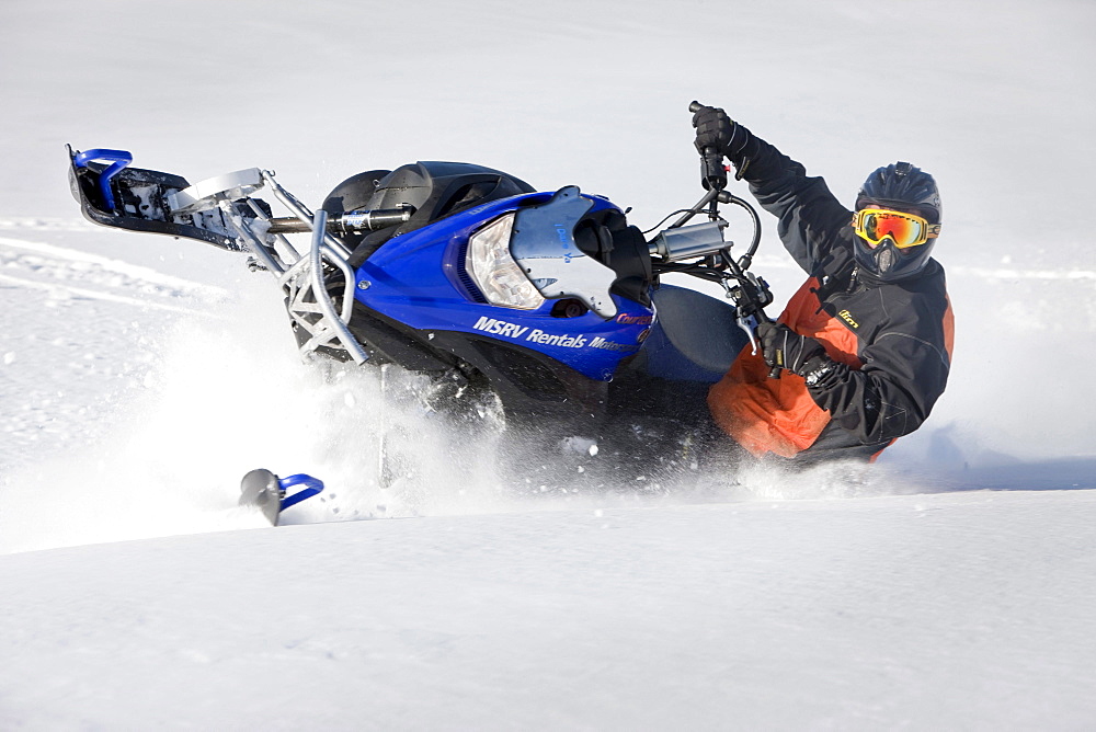 A man makes a sharp turn through powdery snow while snowmobiling on Owlshead Mountain.