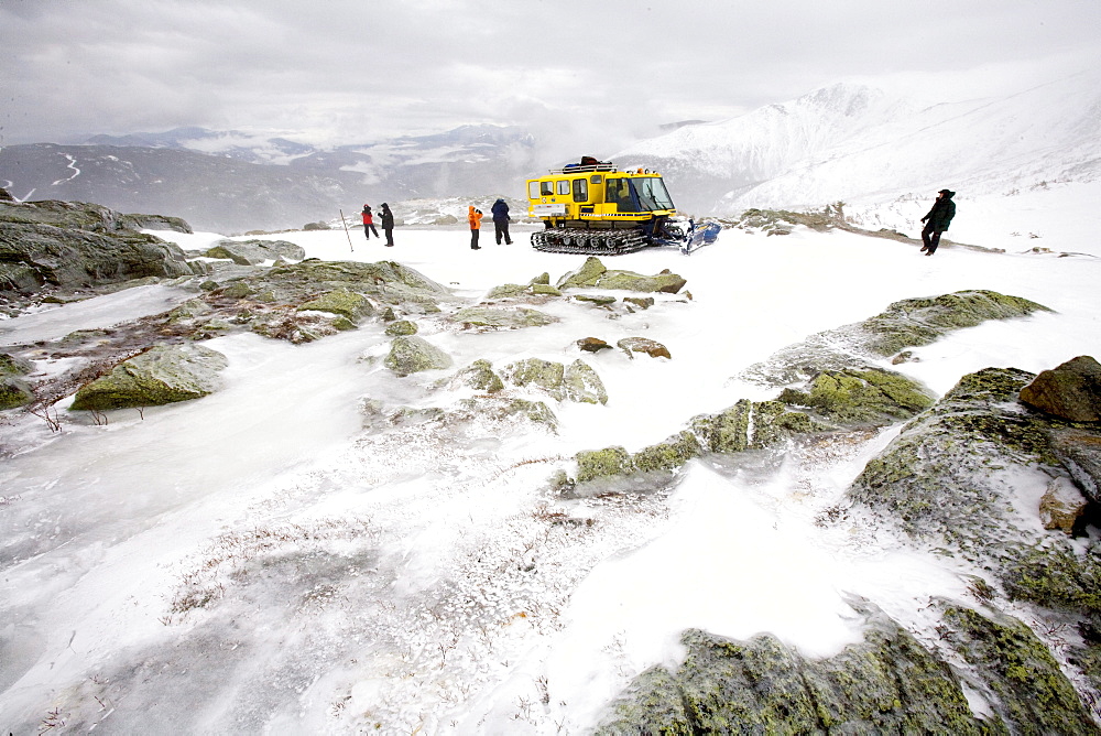 A group of people on a Mt.Washington Observatory educational winter program trip travel up the Auto Road in a snow cat.