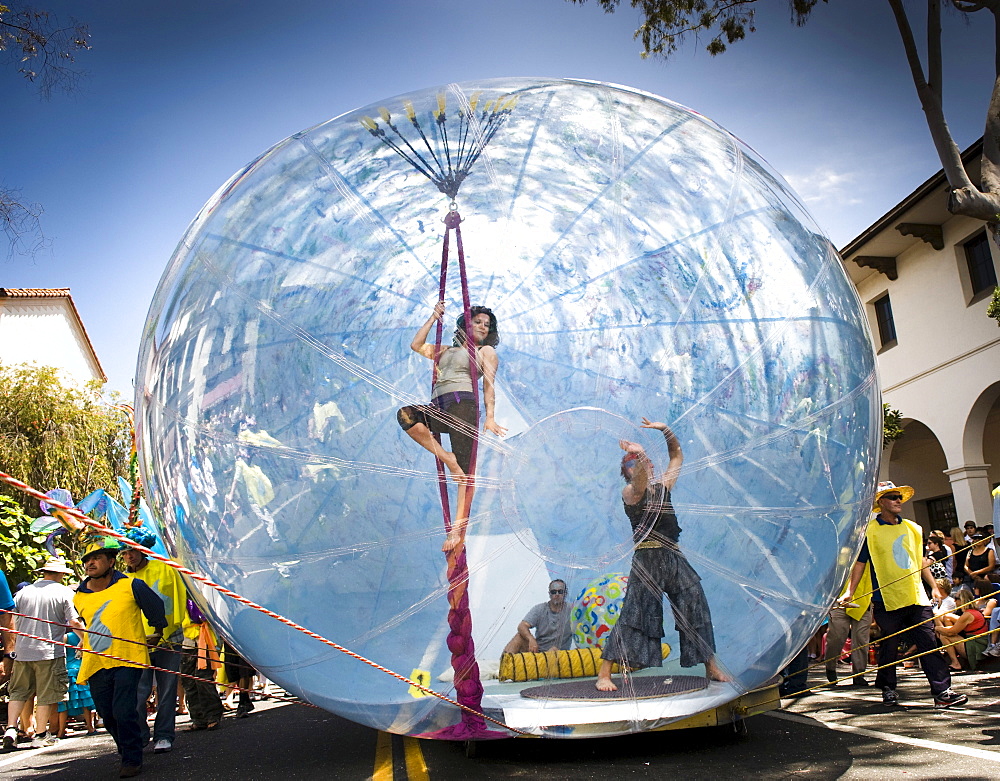 A young woman performs on ropes inside a giant inflatable float at a parade in Santa Barbara.