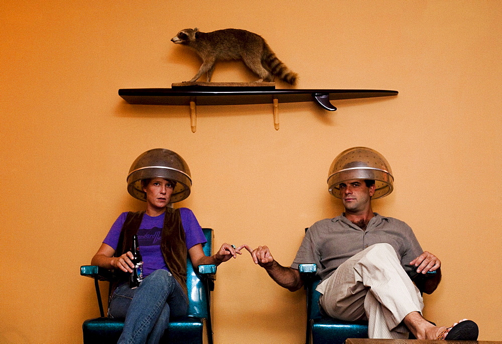 A portrait of a man and a woman with a raccoon above on the wall.