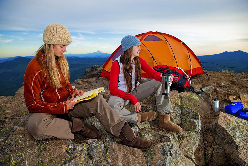 Two young women enjoy the view while camping along Sleeping Beauty in the Pacific Northwest