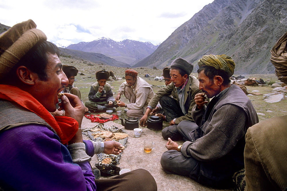 Men of the Wakhi tribe eat bread and drink tea for a meal and rest break during a journey into the Little Pamir from the Wakhan valley, Badakshan, Afghanistan