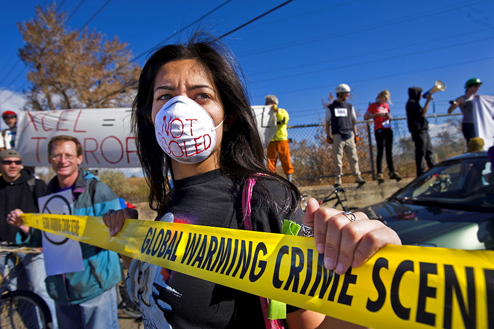 A woman in a mask holds onto a sign during a rally outside of a coal plant that was protesting against coal power and for raising awareness of global warming, on the international day of action promoted by 350.org, October 24, 2009, in Boulder, Colorado