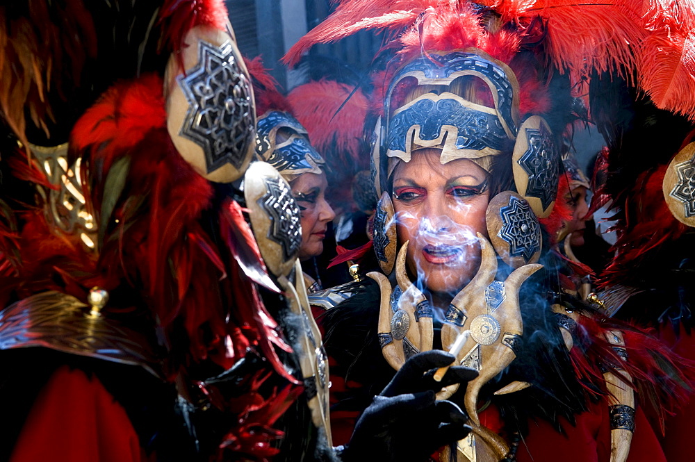 Women dressed in elaborate costumes, loosely representing the North African tribes, the Moors, smoke cigarettes before marching in a parade during the Festival of Moors and Christians, in the old town of Alcoy, Alicante Province, Valencia Autonomous Regio