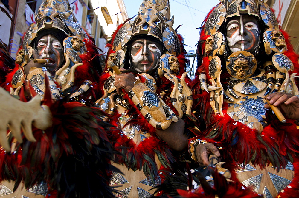 Men dressed in elaborate costumes, loosely representing North African tribes, the Moors, smoke cigars while marching in a parade during the Festival of Moors and Christians, (La Fiesta de Moros y Cristianos) in the old town of Alcoy, Alicante Province.