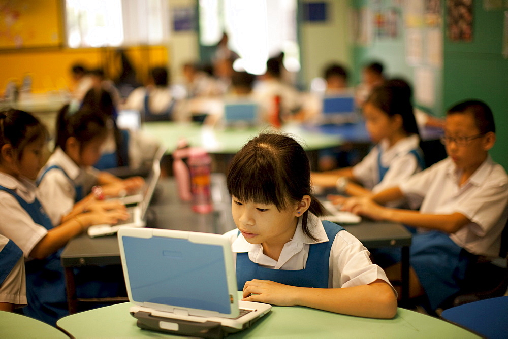 Schoolchildren in 3rd grade at the Canberra Public Primary School use laptops during a summer vacation enrichment class in English.