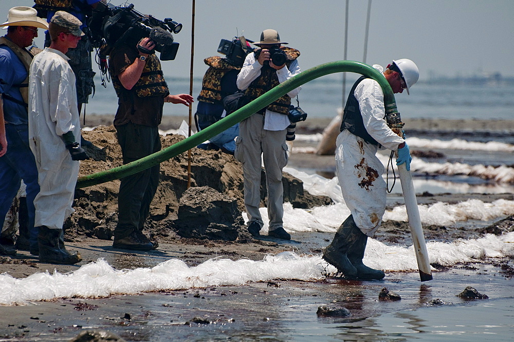 Clean-up crews sucking oil with vacuum tubes and placing absorbent pompom booms.   East Grand Terre was involved in a Barrier Island restoration project before the oil spill.