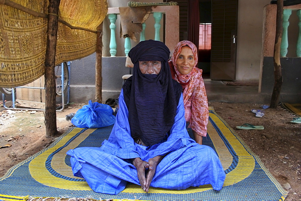 A Muslim Toureg husband and wife sitting on a mat wearing turban and shawl, Mali, West Africa