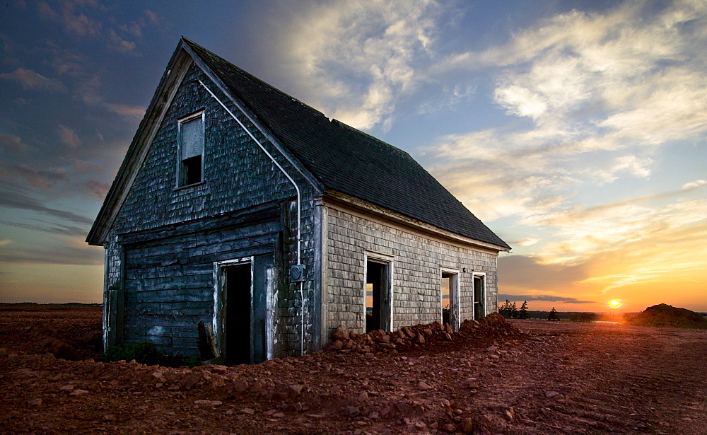 An old farm house sits partially buried as the sun sets in Prince Edward Island, Canada (HDR)