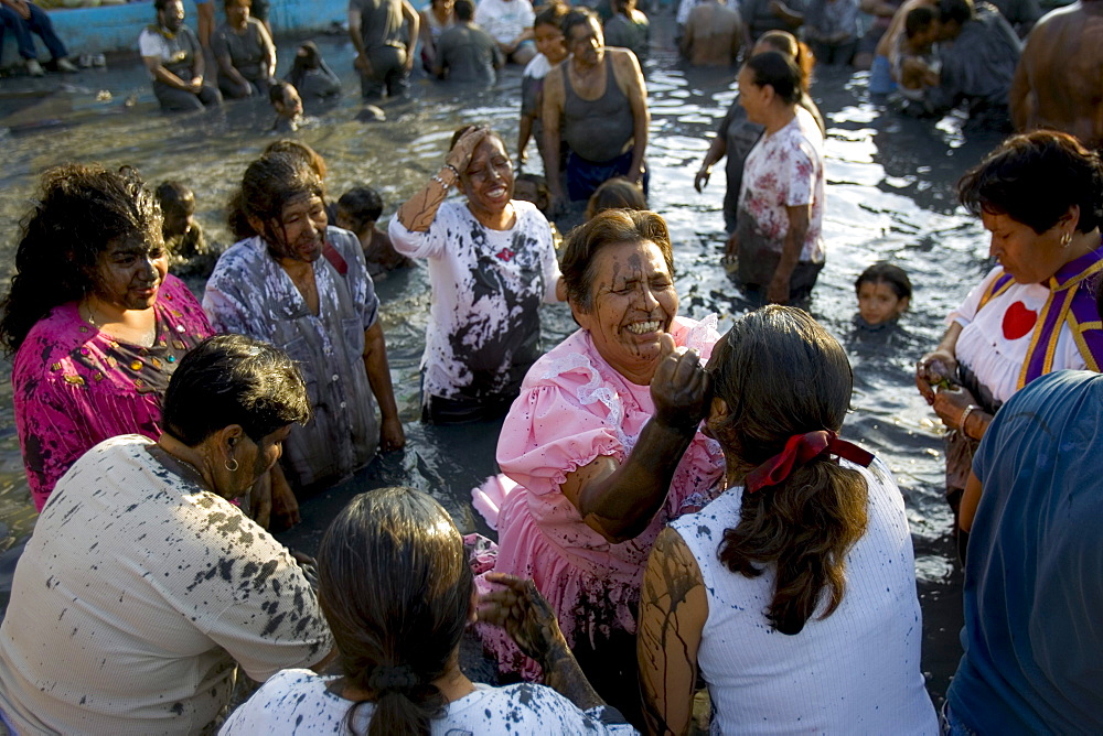 A woman is healed in the mud baths of Espinoza, Mexico.Twice a year the faithful visit Espinazo, a small dusty village and birthplace of El Nino Fidencio, one of the most revered healers in North East Mexico.  Although he died in the 1940s people believe certain priests known as Materias can channel his healing gifts and cure people.  During the anniversary of his birth and death over 100,000 people take part in the celebration by giving thanks at his gravesite or bathing and getting healed in mud baths.