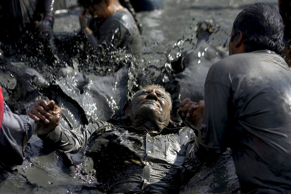 An old man is healed in the mud baths of Espinoza, Mexico.Twice a year the faithful visit Espinazo, a small dusty village and birthplace of El Nino Fidencio, one of the most revered healers in North East Mexico.  Although he died in the 1940s people believe certain priests known as Materias can channel his healing gifts and cure people.  During the anniversary of his birth and death over 100,000 people take part in the celebration by giving thanks at his gravesite or bathing and getting healed in mud baths.