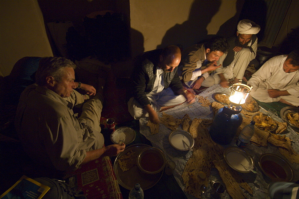 Dr. George Schaller and the other members of his wildlife survey team have dinner in the guest room of the village headman, in the village of Dera Jawal,  Kushk-i Kuhna District, Herat Province, Afghanistan