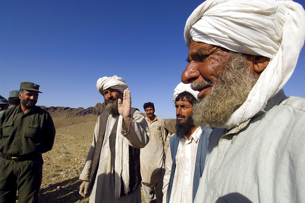 Policemen talk to nomadic Pashtun herders near their camp at the base of the Dau Shakh desert range, outside the town of Gurian, Herat Province