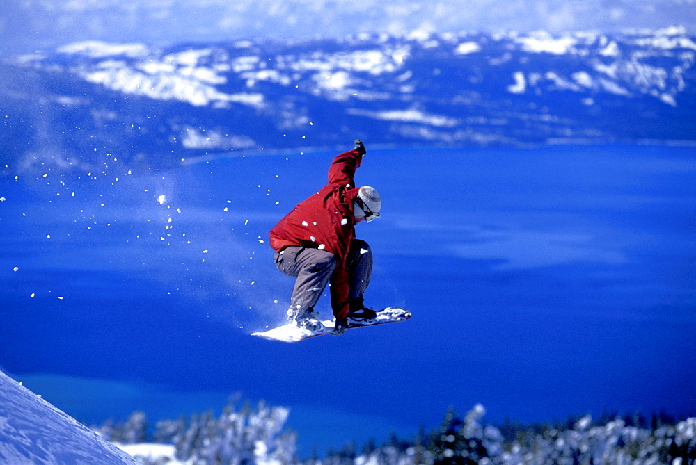 Mikey Wier throwing a grab off of a cliff while snowboarding above Lake Tahoe at Heavenly Mountain Resort in South Lake Tahoe, California.