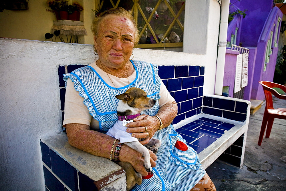 Portrait of a woman posing with her dog on her lap on Isla Mujeres, Mexico.