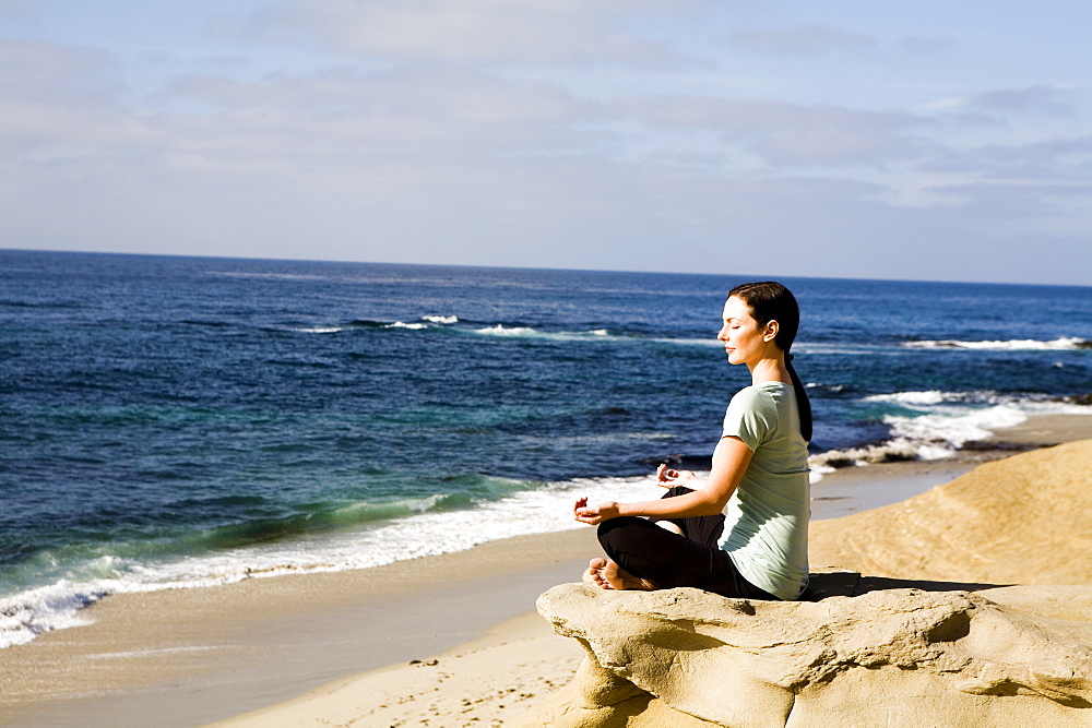 A women meditates on the beach.