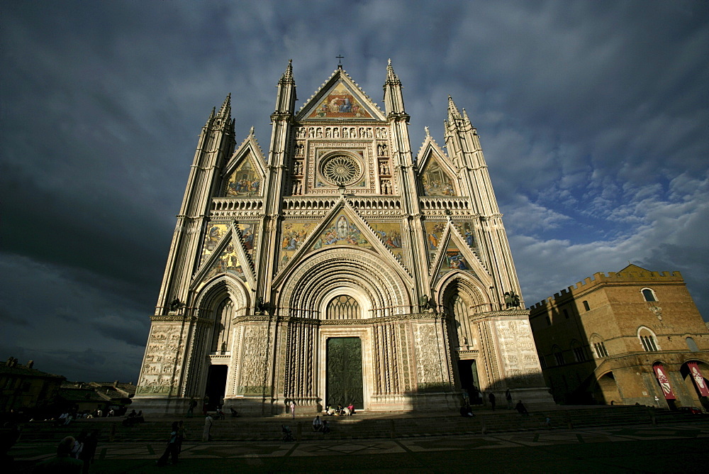 Orvieto, Umbria, Italy, during a late spring sunset.  Orvieto is noted for its Gothic cathedral, or duomo. The church is striped in white travertine and greenish-black basalt in narrow bands; its design has often been attributed to Arnolfo di Cambio, but the prevailing modern opinion is that its master mason was an obscure monk named Fra' Bevignate from Perugia; construction began in 1290.