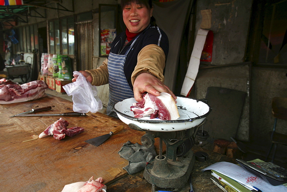 A woman sells a fatty cut of pork in a market in Songzhuang Village, in Beijing's eastern suburbs, China.