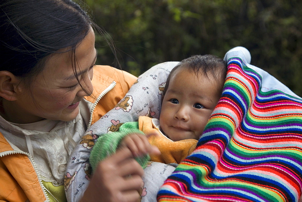 The daughter of an apple vendor holds her baby sibling along the road near Lijiang, A historic city in Yunnan Province, China.