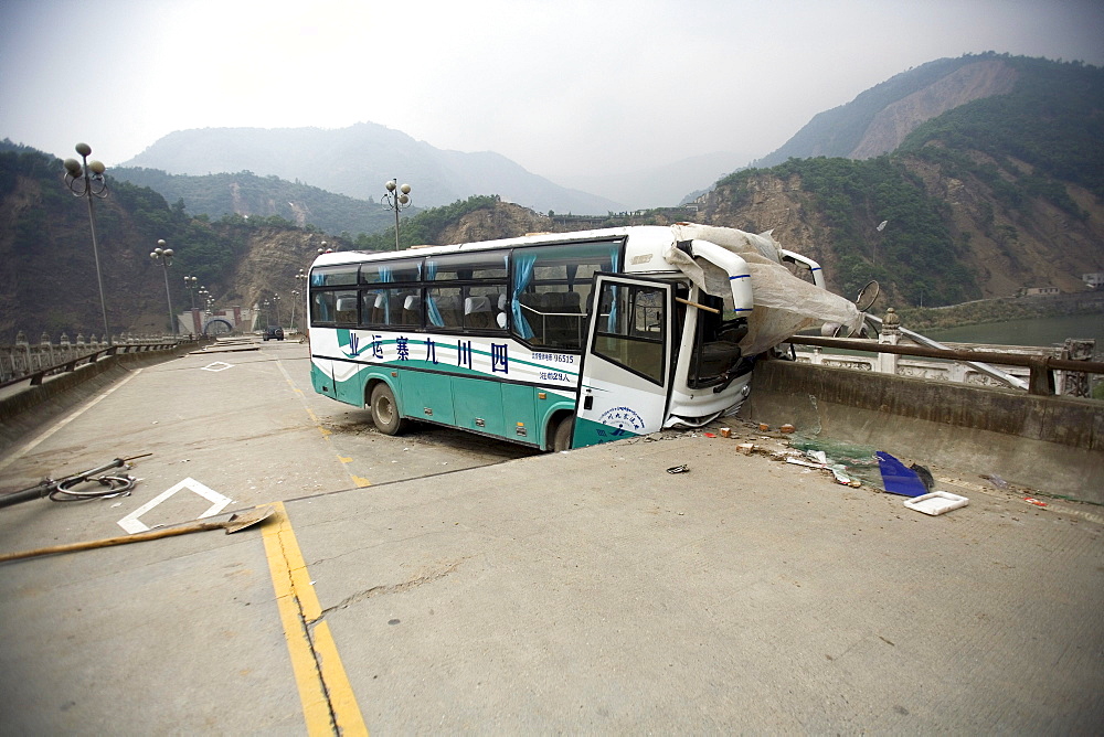 A bus is seen on a road wrecked by Monday's powerful earthquake.  The Chinese government raised the death toll to 21,500 but has said fatalities could rise above 50,000. Tens of thousands could still be buried in collapsed buildings in Sichuan province, where the quake was centered.