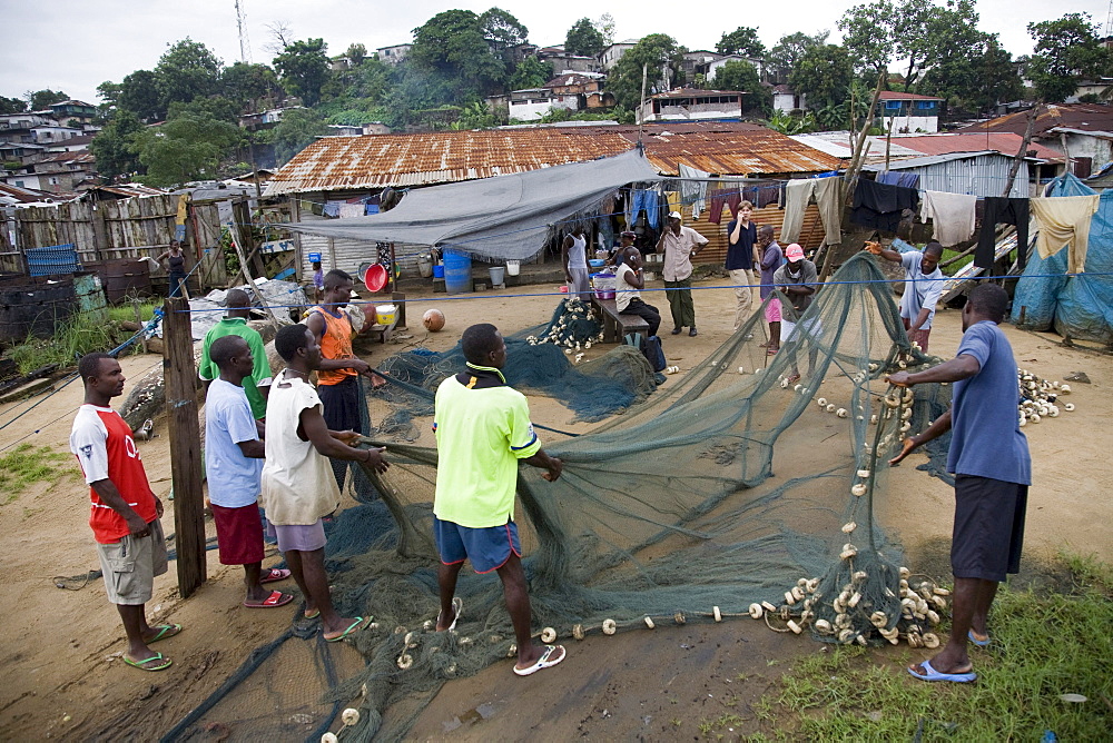 Monrovia, Liberia - September 18, 2007: Fishermen in West Point , Monrovia, Liberia sorting out, mending and picking trash out of their fishing nets. The fishing industry is an important source of employment and food for Liberians and is increasingly under threat by better equipped and unregulated foreign vessels over fishing in its unprotected waters.