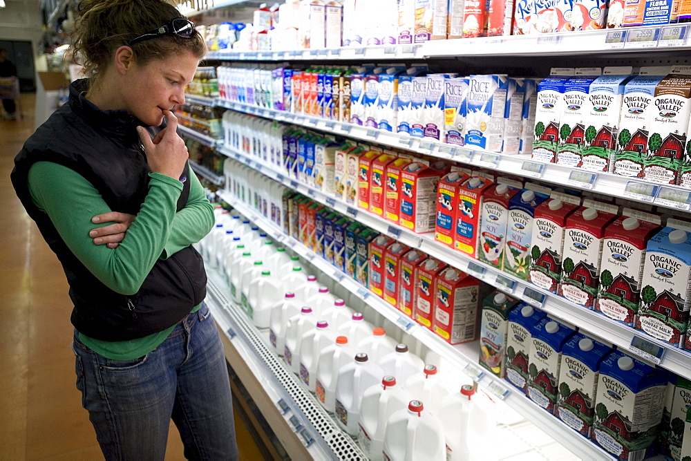 A young woman looking upset at the cost of milk in a grocery store in Bend, Oregon.