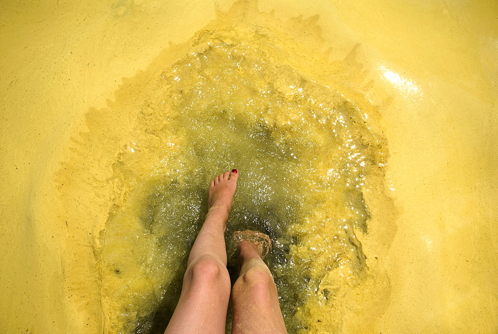 Feet dip in pollen covered lake water, Sebago Lake, Maine.