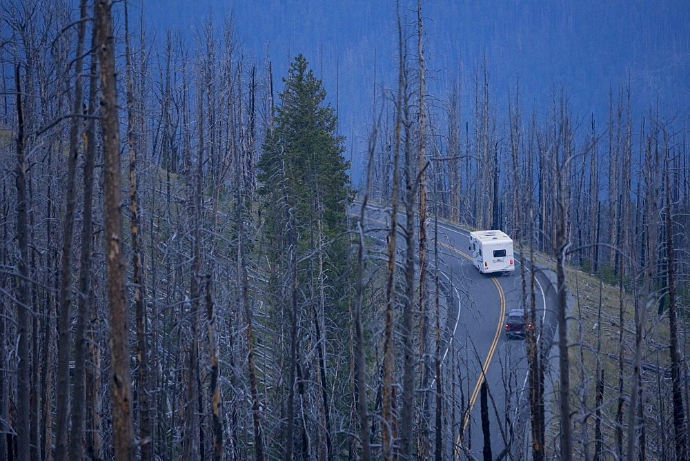 A camper and car travel through Yellowstone National Park in Wyoming.