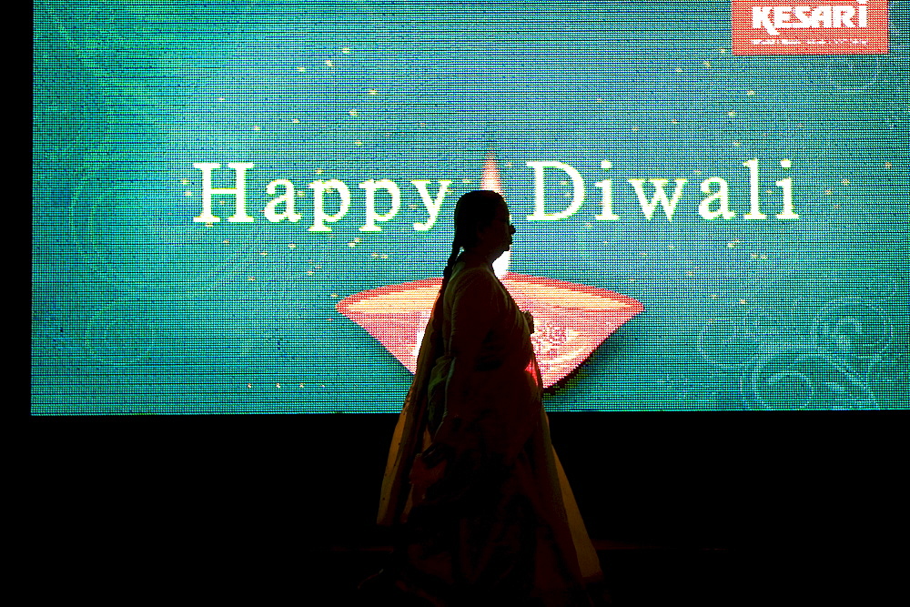 A silhouette of a woman walking in front of an electronic billboard wishing a happy Diwali to passerby's in Mumbai, India. Diwali is a major Hindu holiday and is known as the "Festival of Lights".  The five day festival occurs during October and/or November.