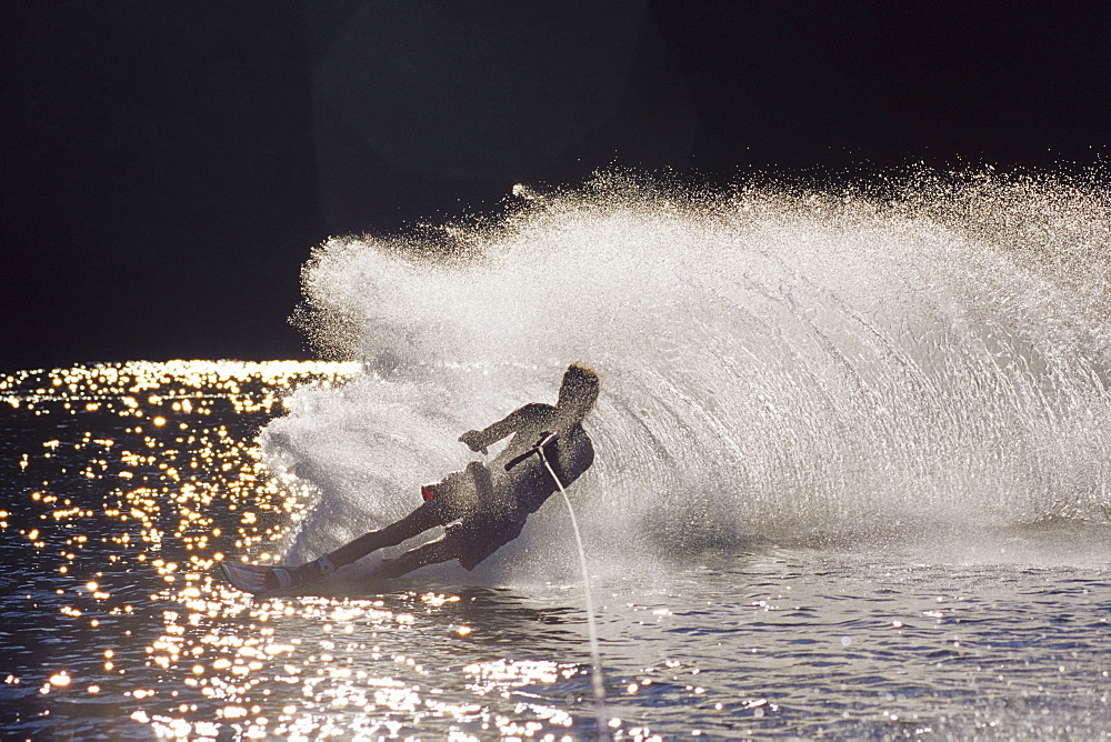 Male water skier backlit by the sun.