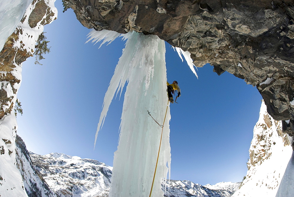 A professional male climber ascends a frozen waterfall pillar while ice climbing near Ouray, Colorado.