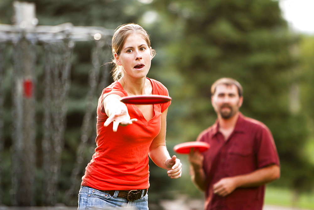 A man and woman play disk golf.