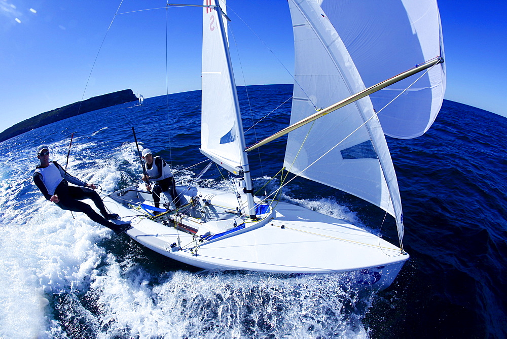 Two male athletes sail an Olympic class racing boat in Sydney Harbor, Australia.