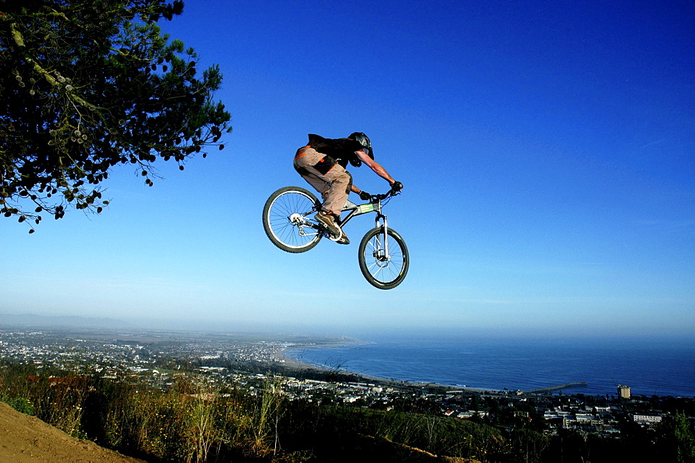 A young man goes off a jump on a mountain bike in the hills overlooking Ventura, California.