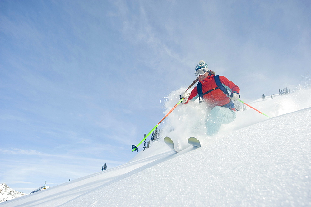 A woman skier smiles as she skis the powder in the backcountry of the Selkirk Mountains, Canada.