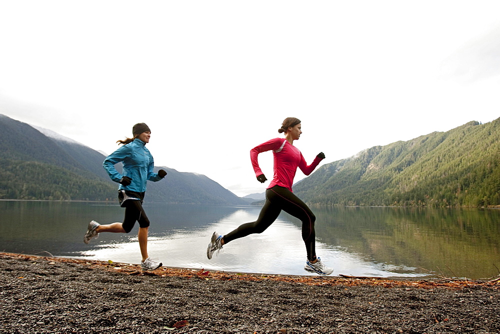 Two females jogging together along the shore of Lake Crescent.