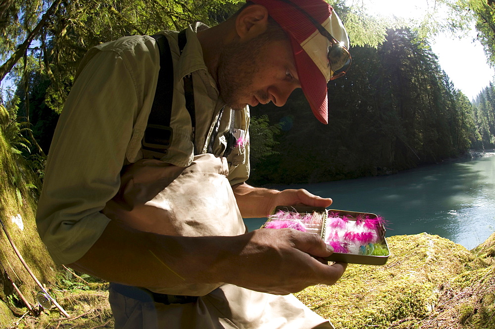 A man picks a fly from his fly box while  fishing in Squamish, British Columbia.