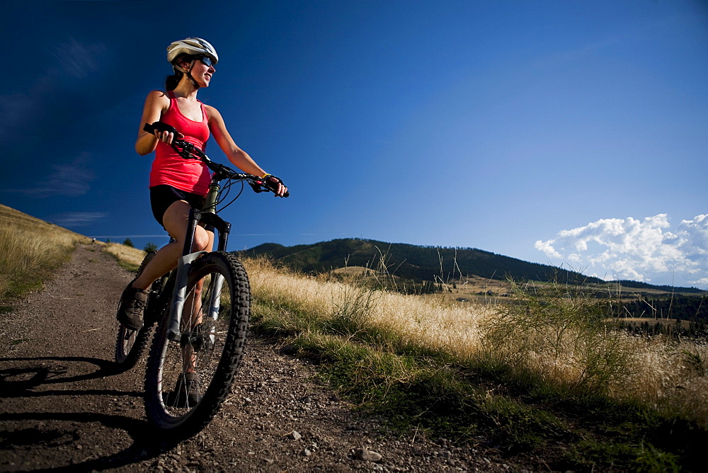 A female mountain biker stops to enjoy the view while riding the trails of Mt. Sentinel, Missoula, Montana.