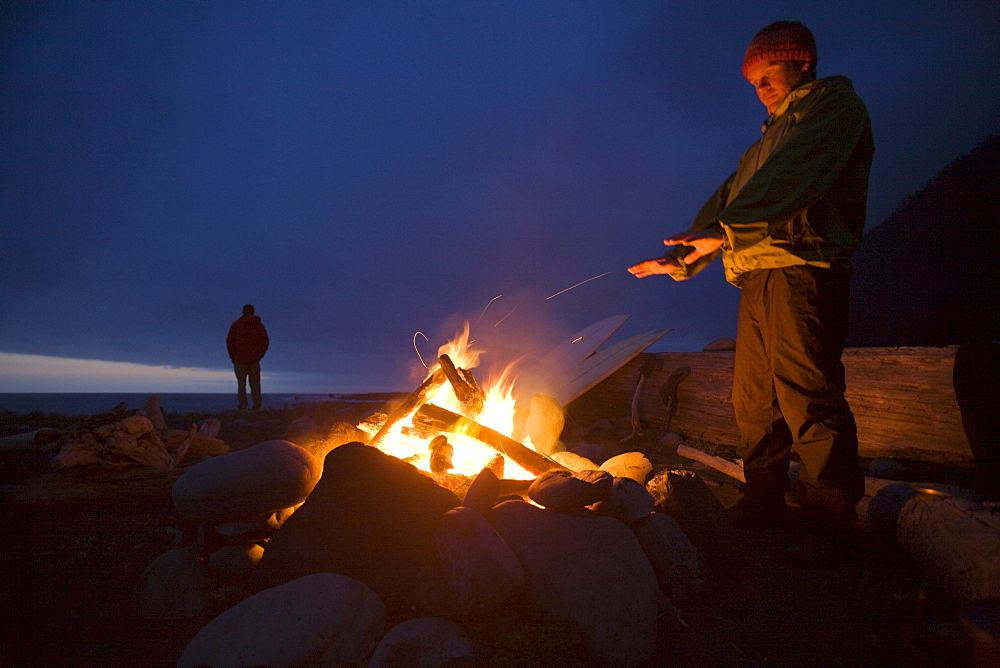 Two men stand around a camp fire on The Lost Coast, California.