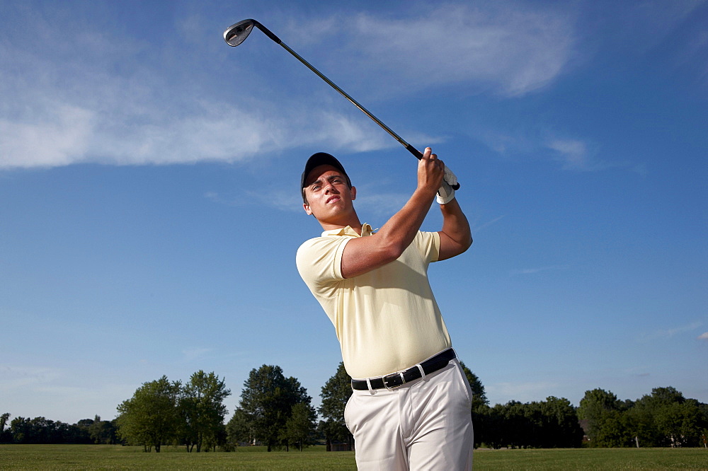 A male golfer swinging his club.