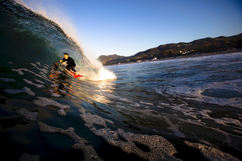 A male surfer gets barreled at Zuma beach in Malibu, California.