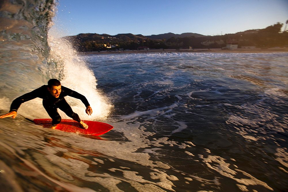 A male surfer gets barreled at Zuma beach in Malibu, California.