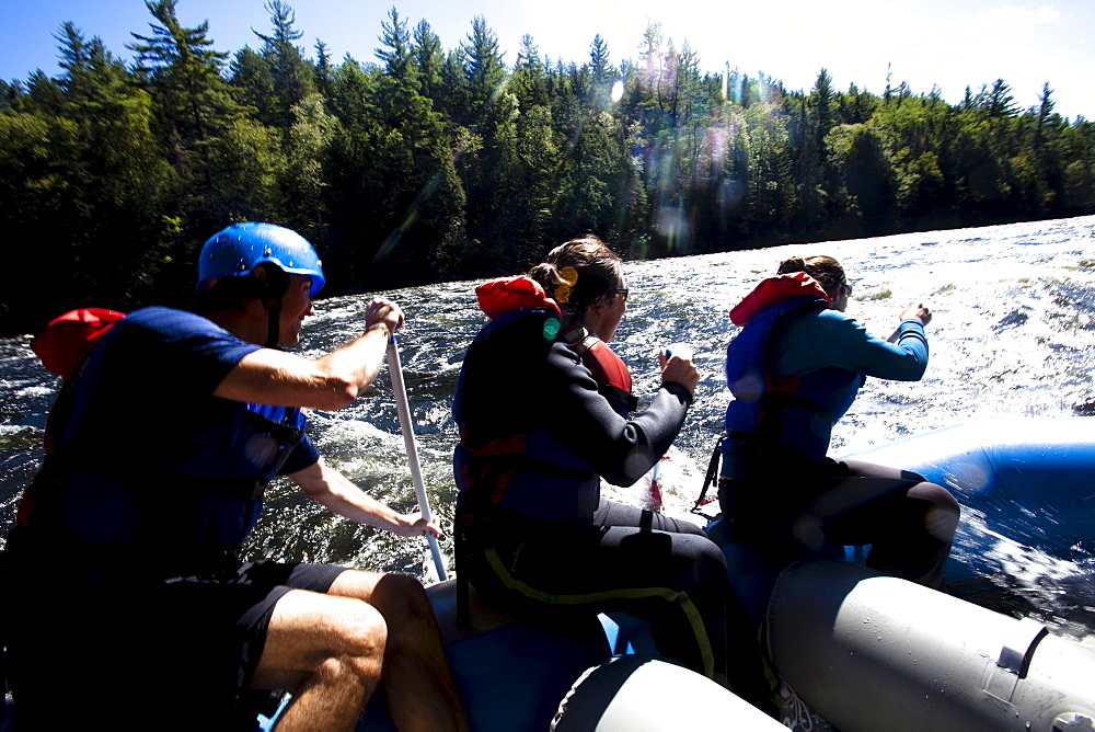 A group of adults whitewater rafting in Maine.