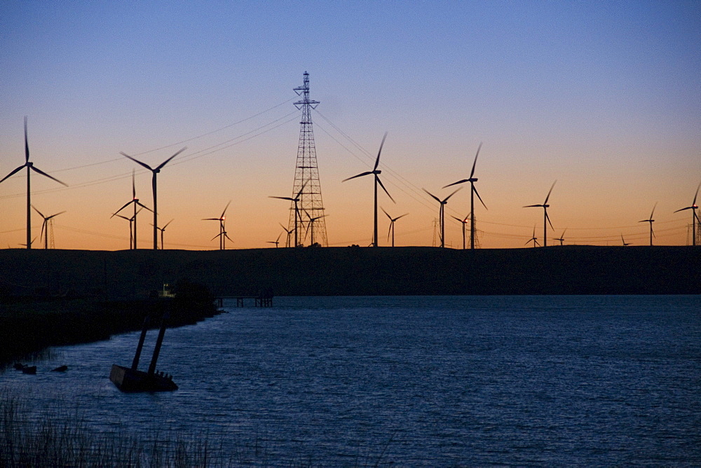 Wind turbines and power transmission lines at sunset near San Francisco