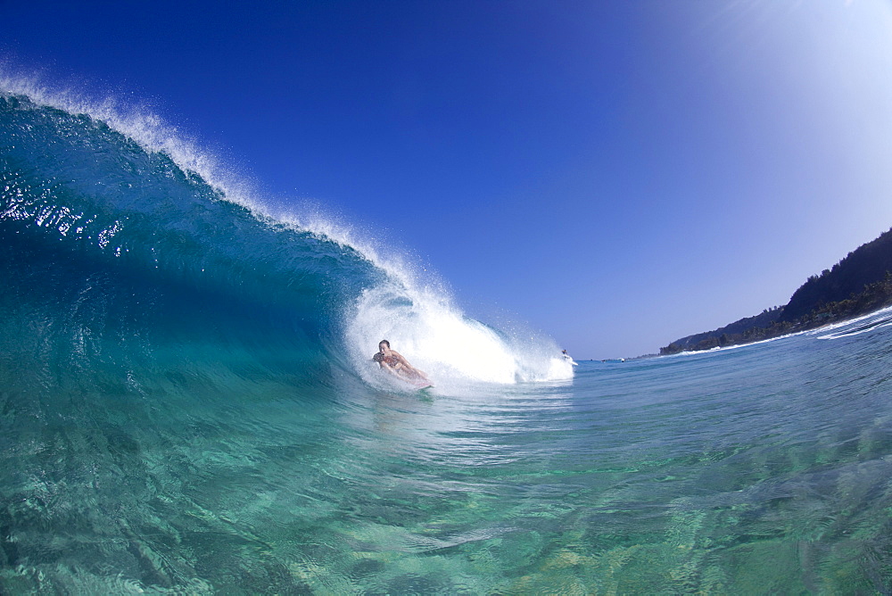 A water view of a surfer girl in the tube, in Hawaii.