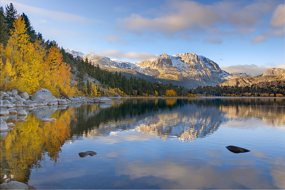 Yellow aspens clouds and a mountain  reflecting in June Lake in the fall in the Sierra mountains of California