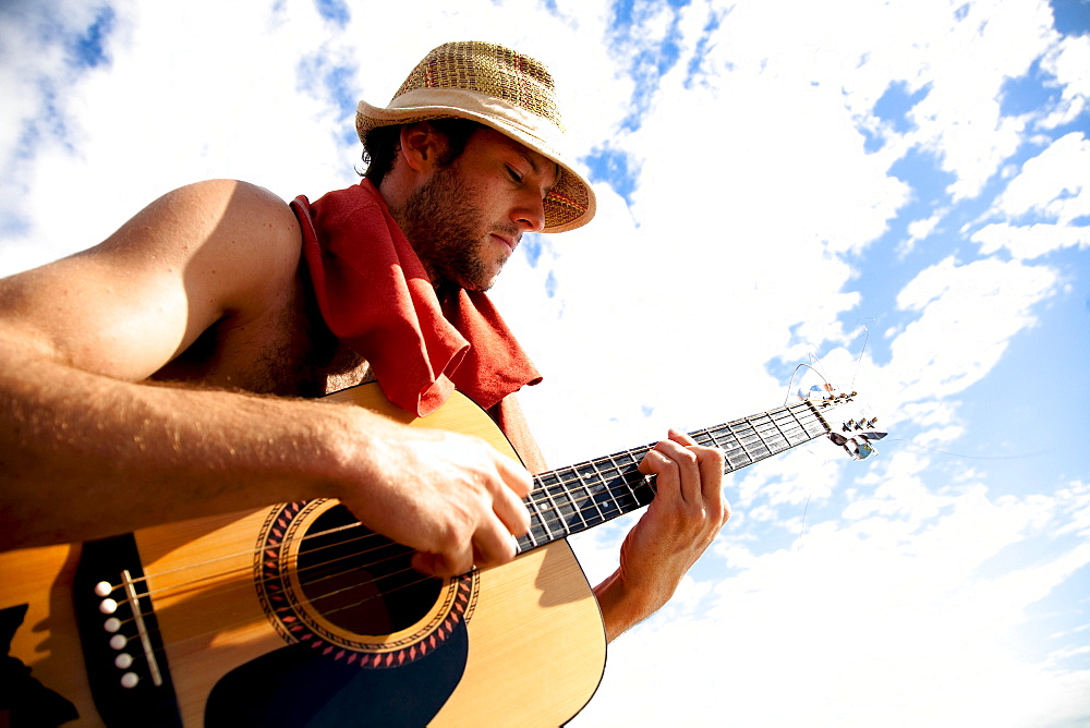 A young man plays his guitar while on a fishing boat off the coast of Malakati, Fiji.